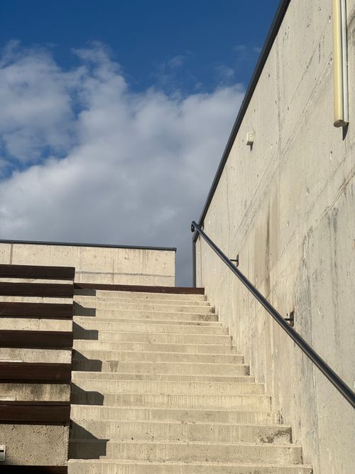 Free Modern concrete staircase ascending towards a bright blue sky with fluffy clouds. Stock Photo