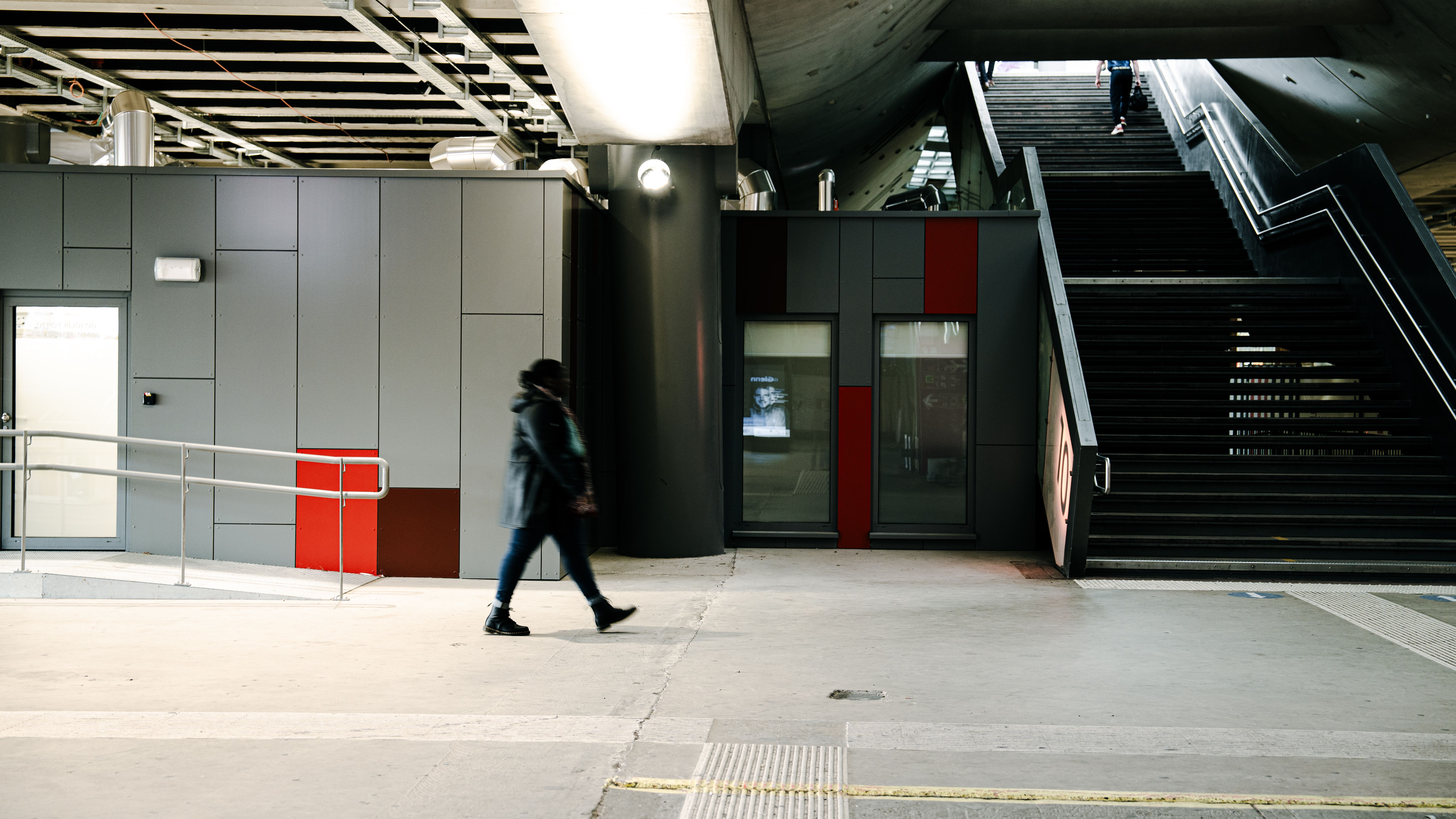 A person walks past modern architectural structure and stairs.