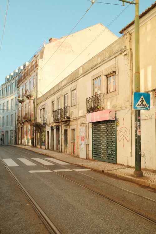 Free Empty street in Lisbon, Portugal with traditional architecture and tram lines at sunrise. Stock Photo