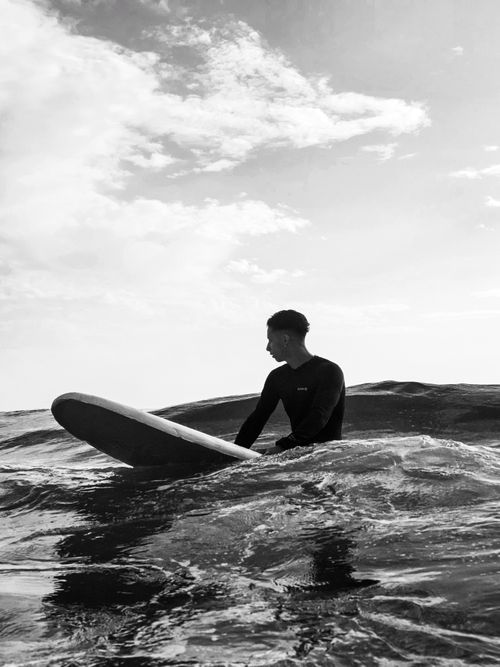 Free A surfer on a board navigating ocean waves in black and white. Stock Photo