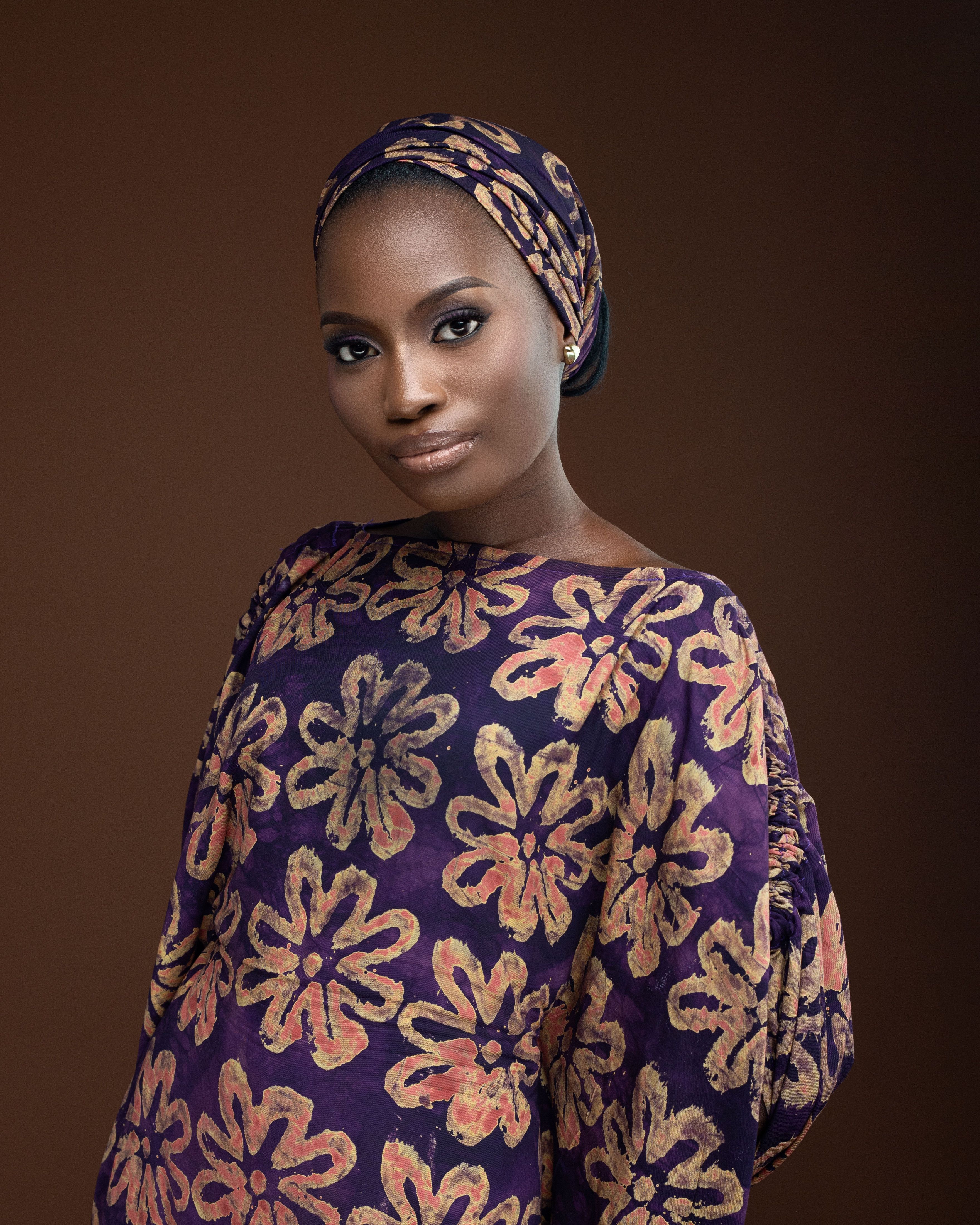 Beautiful portrait of a woman in floral traditional attire against a brown background.