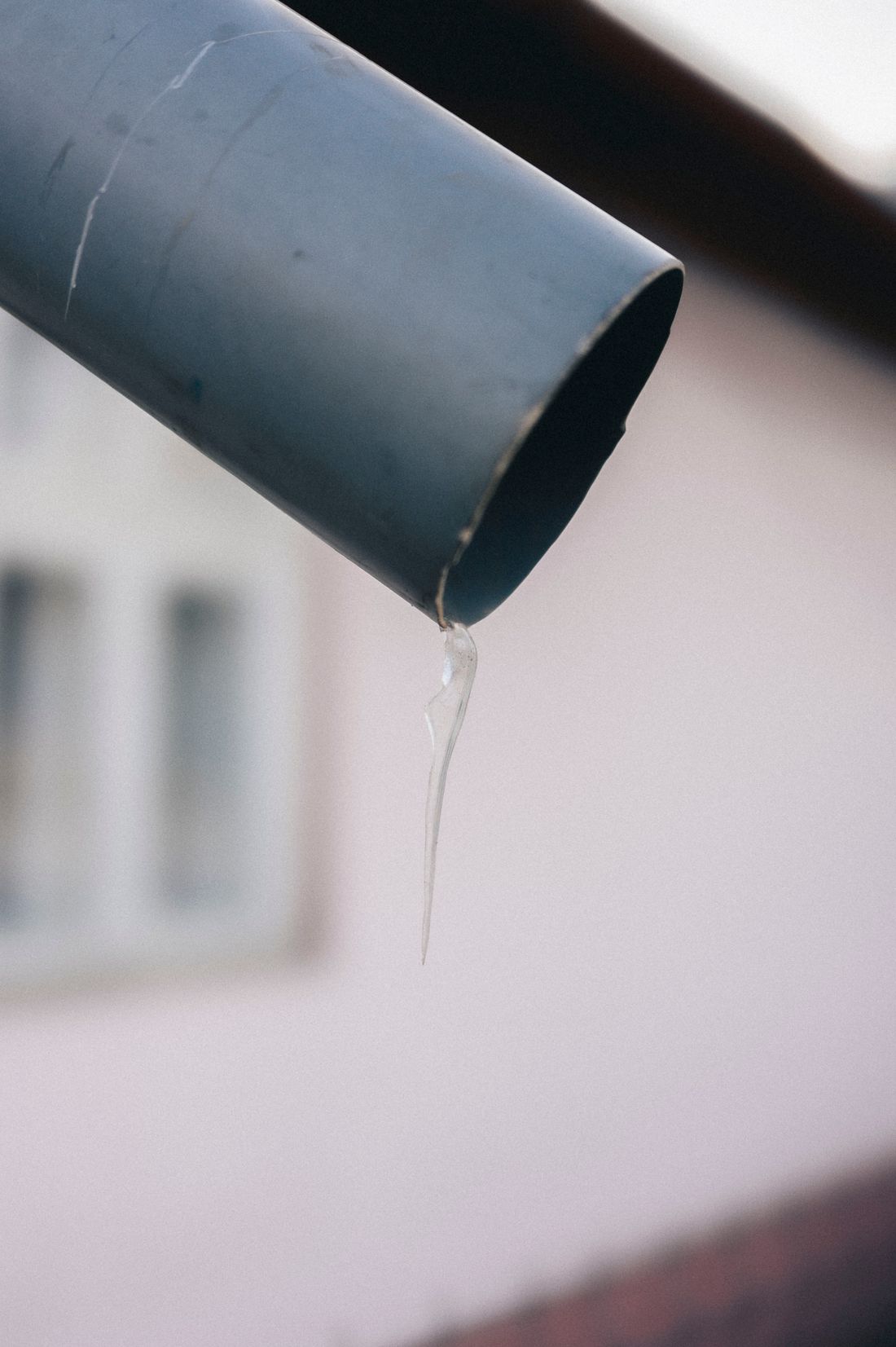 Water dripping from the lip of a metal gutter