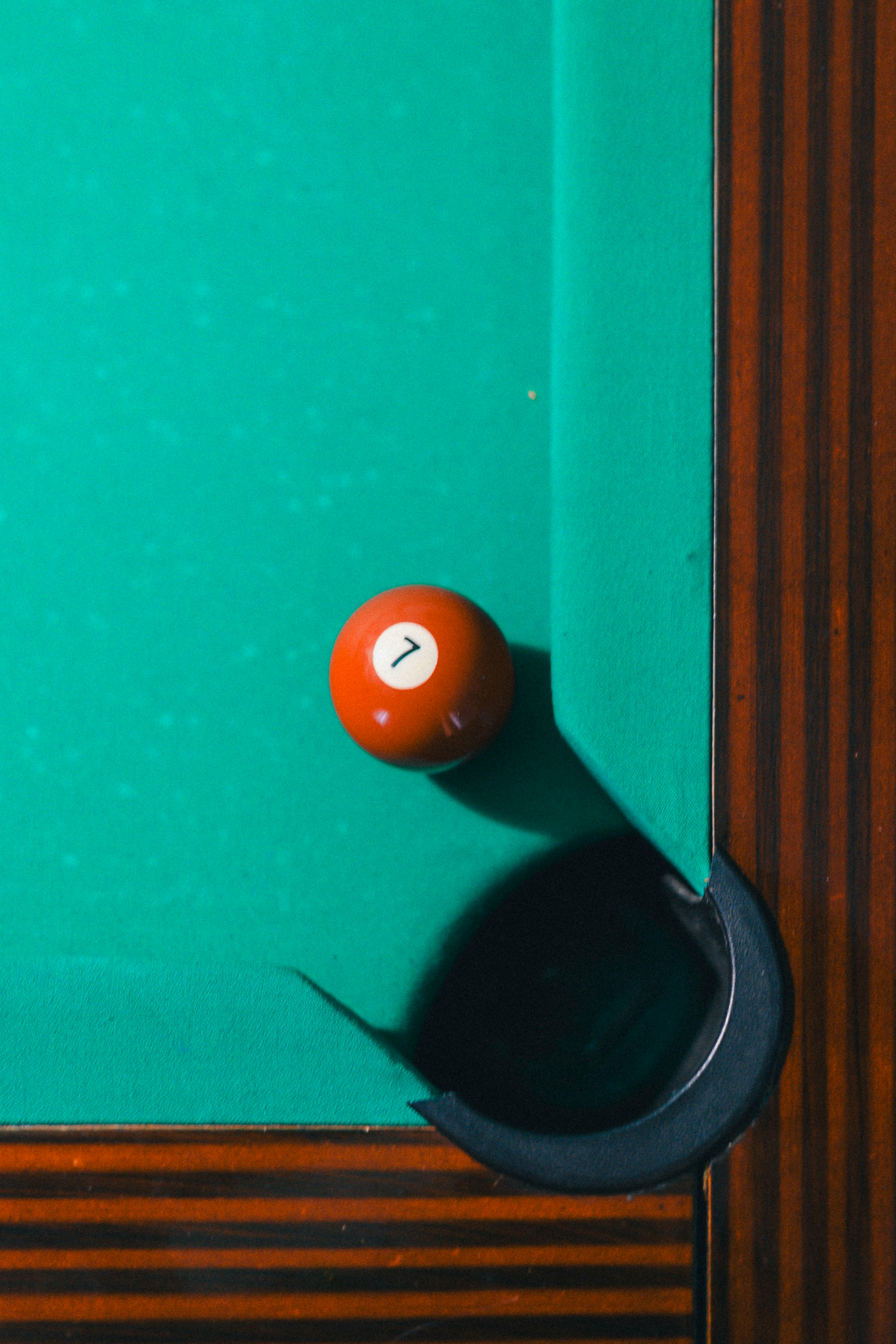 A detailed close-up of a pool table featuring a seven ball near the pocket, showcasing skillful play.