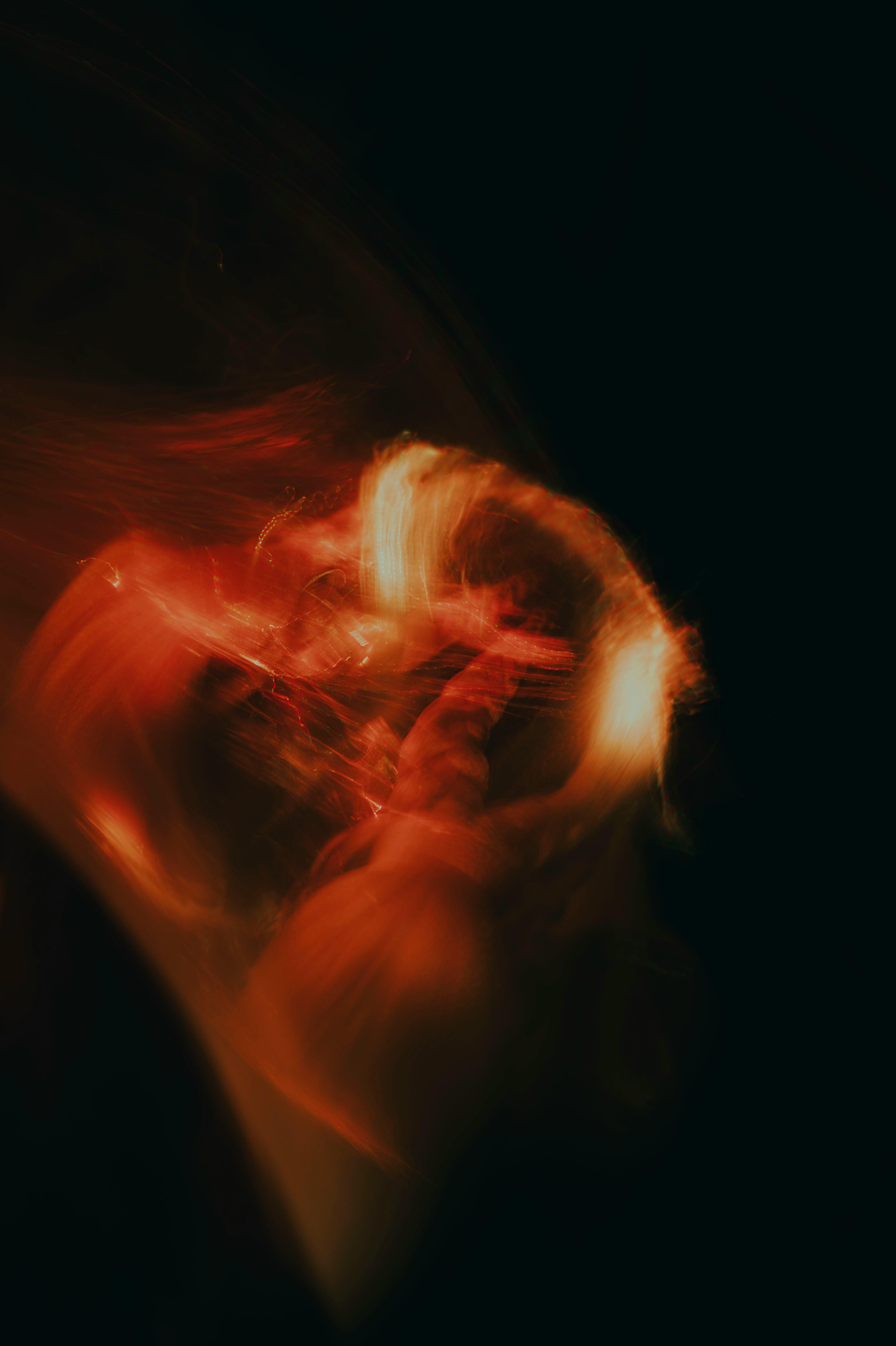 gratis Een adembenemend abstract lichtschilderij met levendige, warme tinten in beweging tegen een donkere achtergrond. Stockfoto