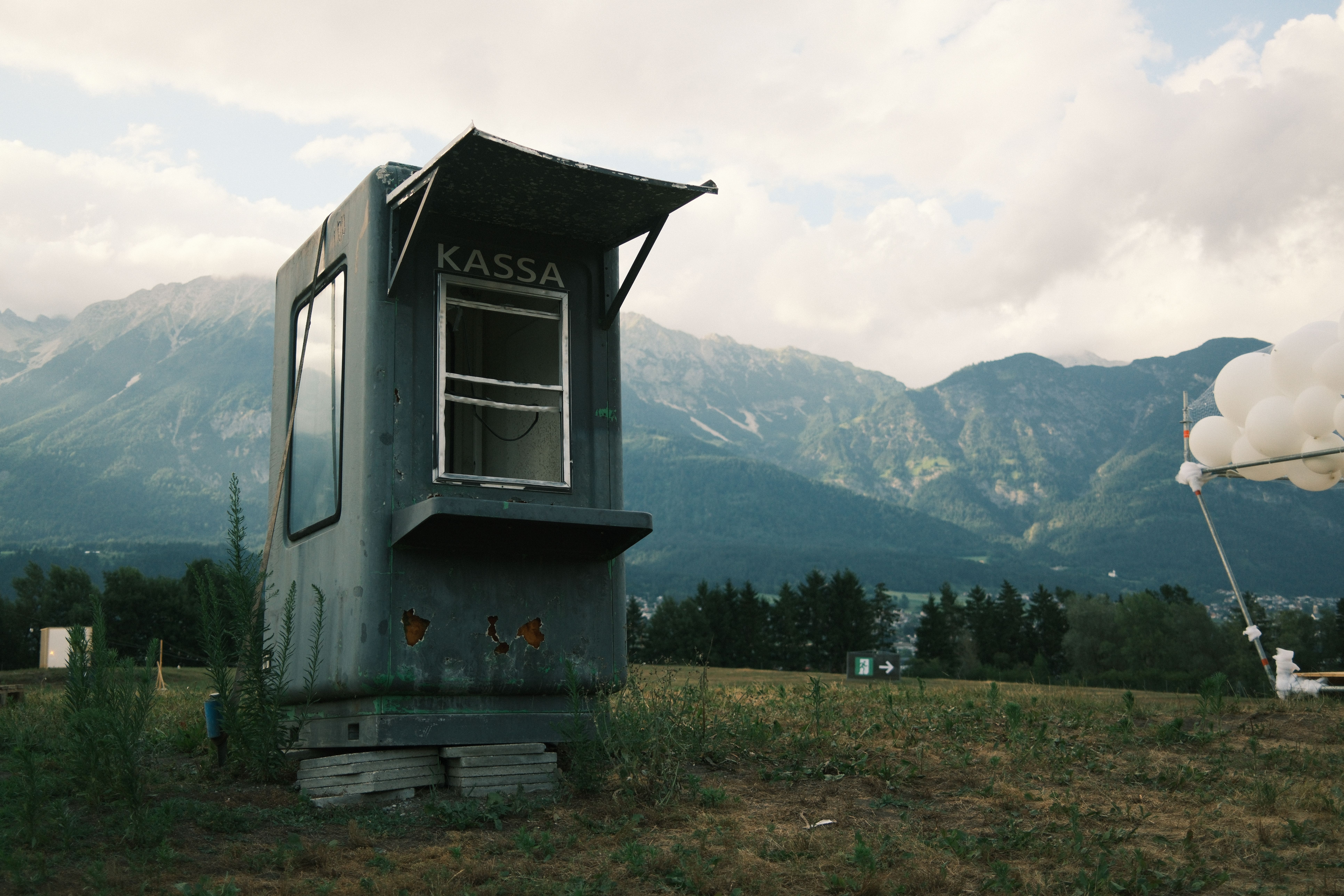 Abandoned ticket booth against the stunning backdrop of Innsbruck's mountains.