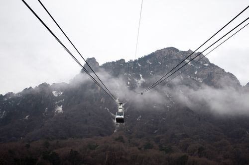 Free Cable car traversing misty mountainous landscape, offering a scenic aerial view. Stock Photo