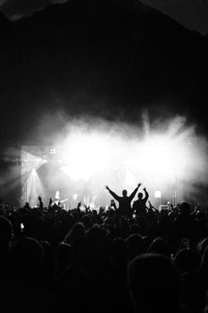 A lively night concert in Innsbruck, capturing silhouettes of a cheering crowd against bright stage lights.
