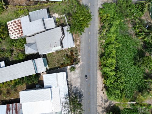 Free Aerial view showcasing a quiet rural road alongside houses in Vietnam's lush countryside. Stock Photo