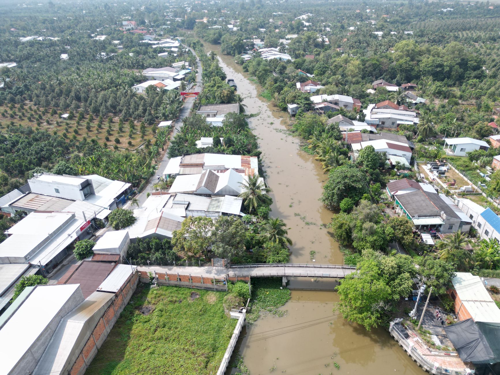 Explore the lush greenery and winding river of a Vietnamese village from above.