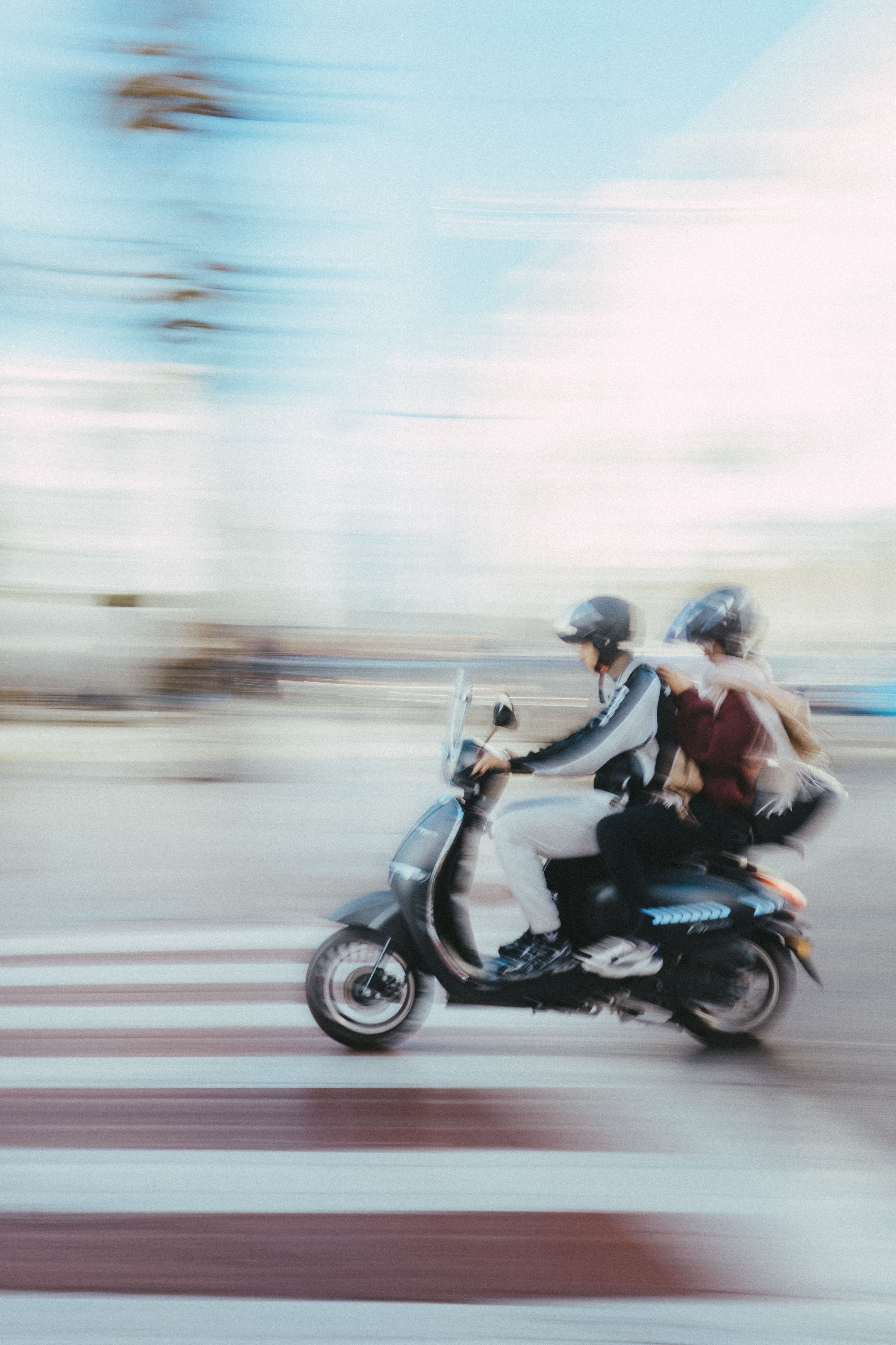Motion-blurred image of two people riding a scooter through a city street in Rabat, Morocco.