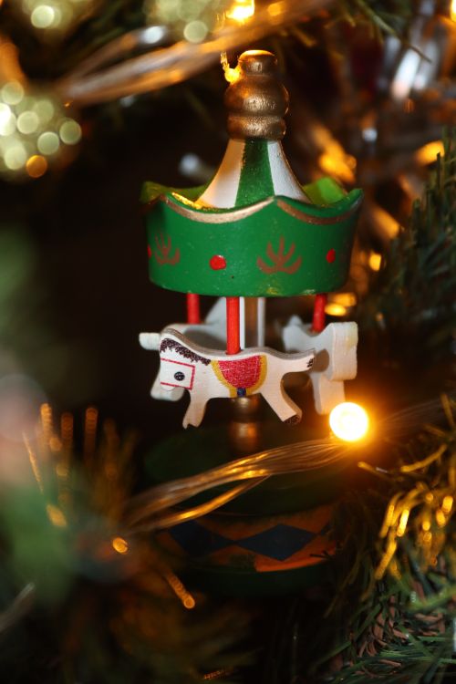 Free Close-up of a colorful carousel ornament on a Christmas tree with warm lights. Stock Photo