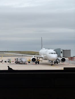 Airplane parked at airport gate during overcast weather, ready for boarding.