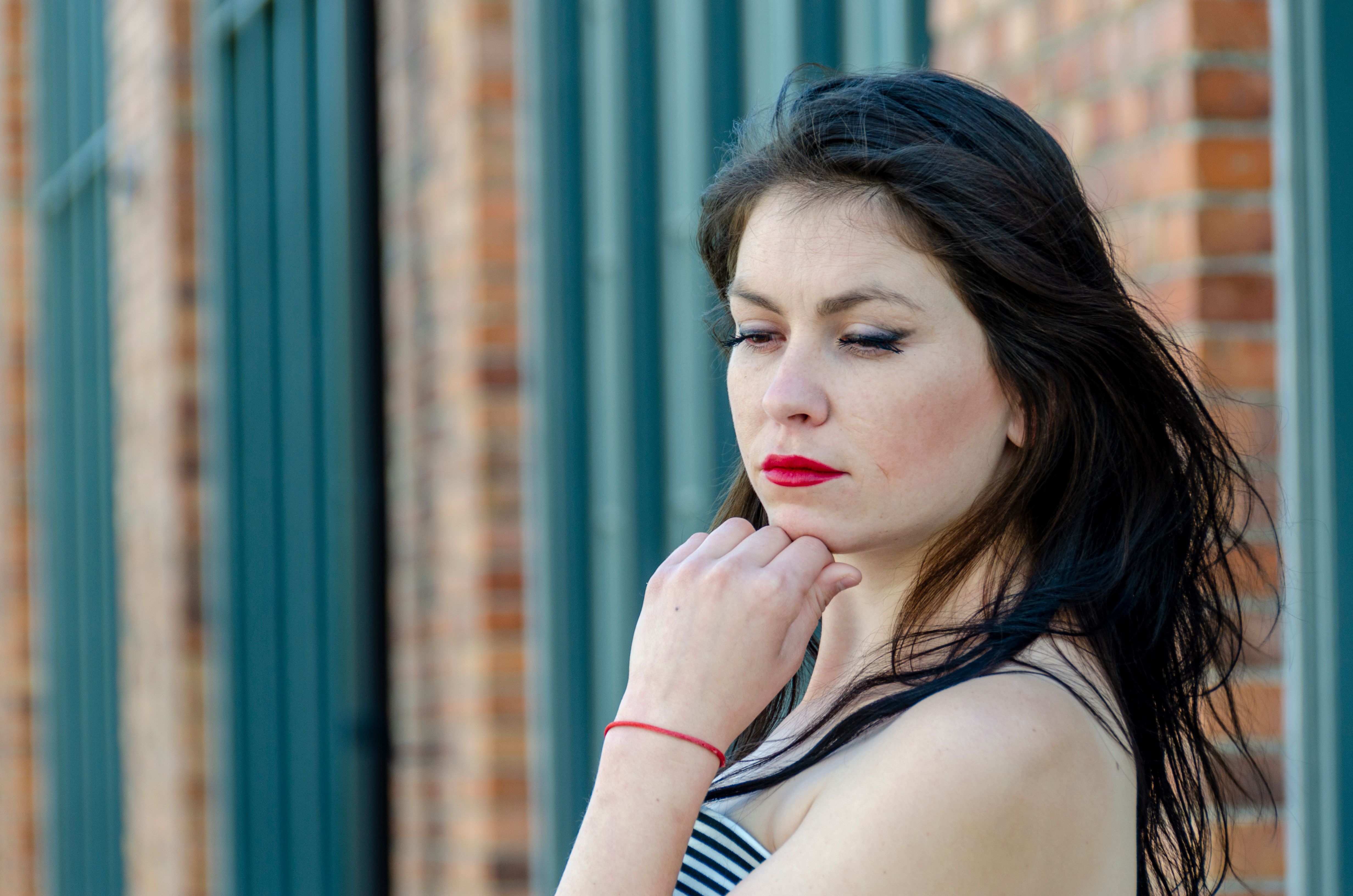 Portrait of a woman reflecting outdoors in Stockholm, Sweden, with a brick wall background.