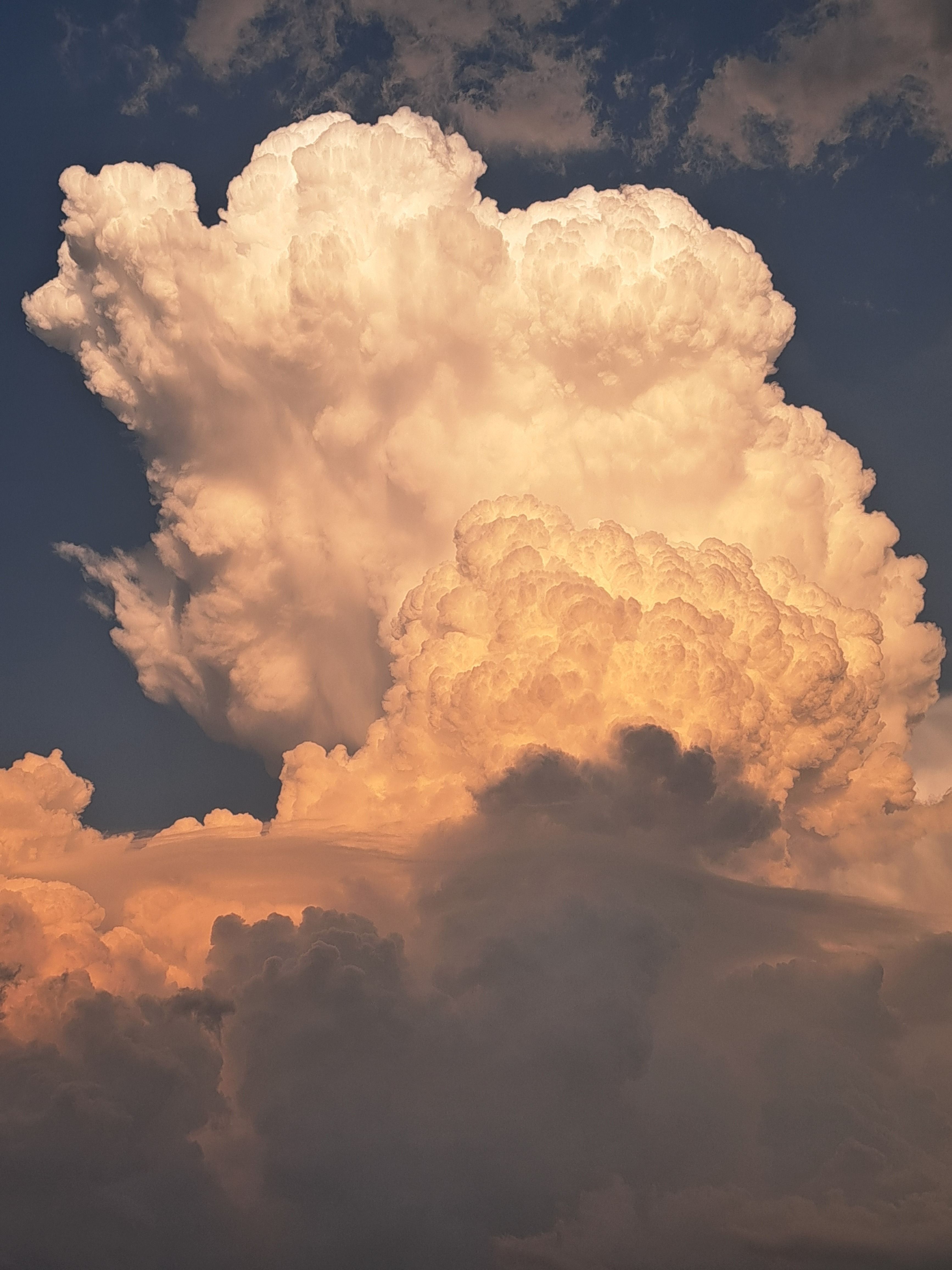 A towering cumulus cloud illuminated by sunset, creating a dramatic sky.
