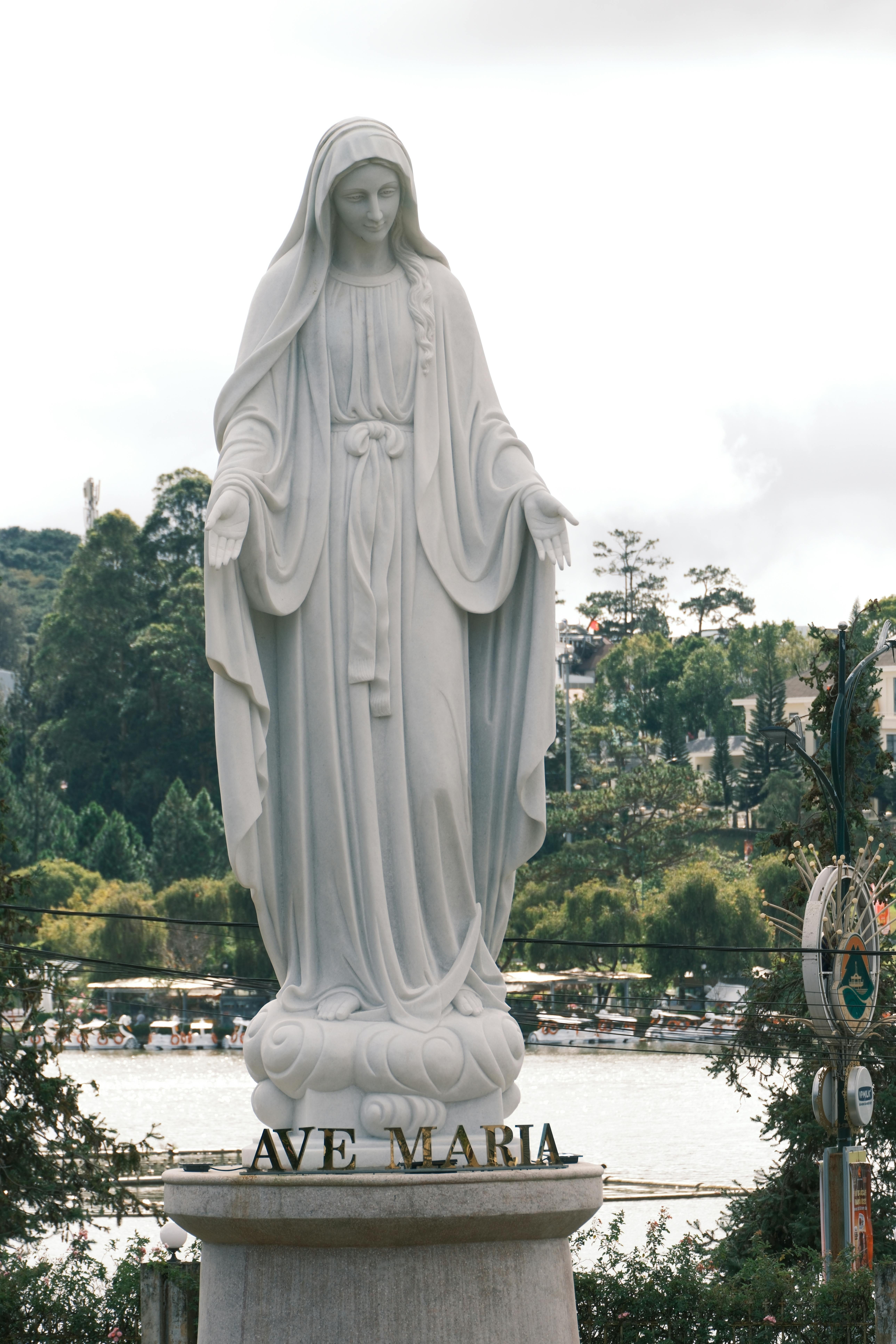 A serene statue of Ave Maria set against a lush natural backdrop, symbolizing peace.