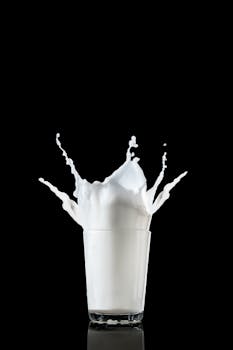High-speed photograph capturing a splash of milk in a glass against a stark black background.