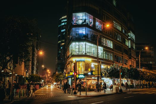 Busy city street at night with bustling nightlife and illuminated buildings.