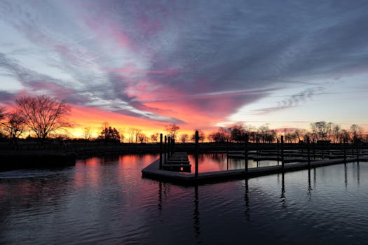Stunning sunrise over an empty dock with vibrant skies reflected on the lake's surface.