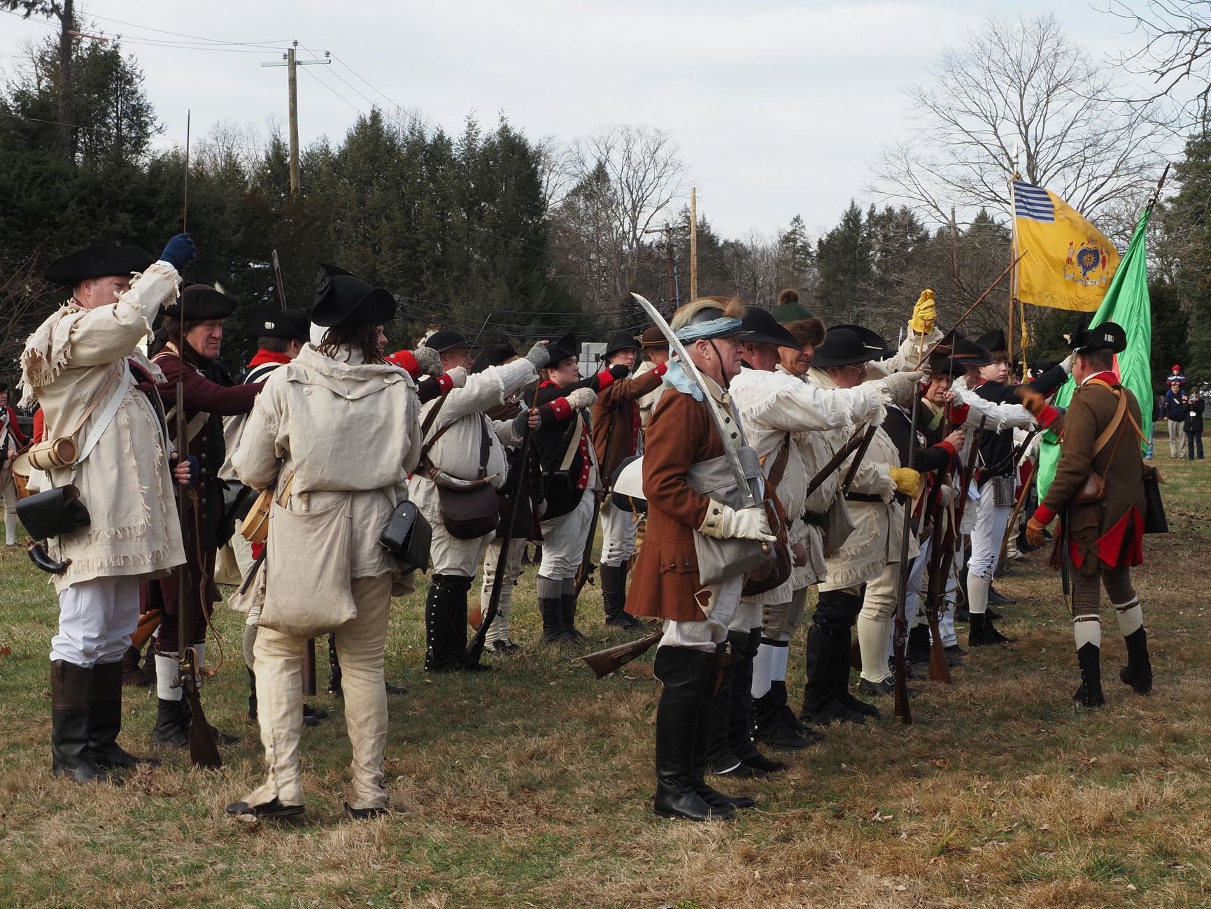 Reenactors in colonial attire perform a Revolutionary War battle re-enactment outdoors.