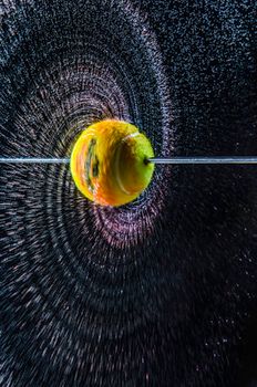 Dynamic apple spinning with vibrant water splash creating a stunning circular pattern against a dark backdrop.