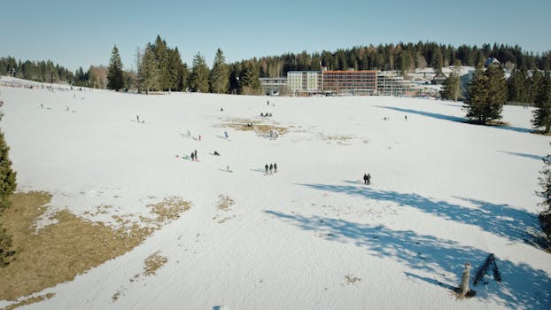 Drone view of Feldberg, Germany showcasing a winter wonderland with snow-covered fields and distant buildings.