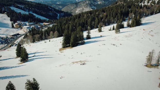 Aerial view of a snowy winter landscape at Feldberg, Germany with people enjoying outdoor activities.