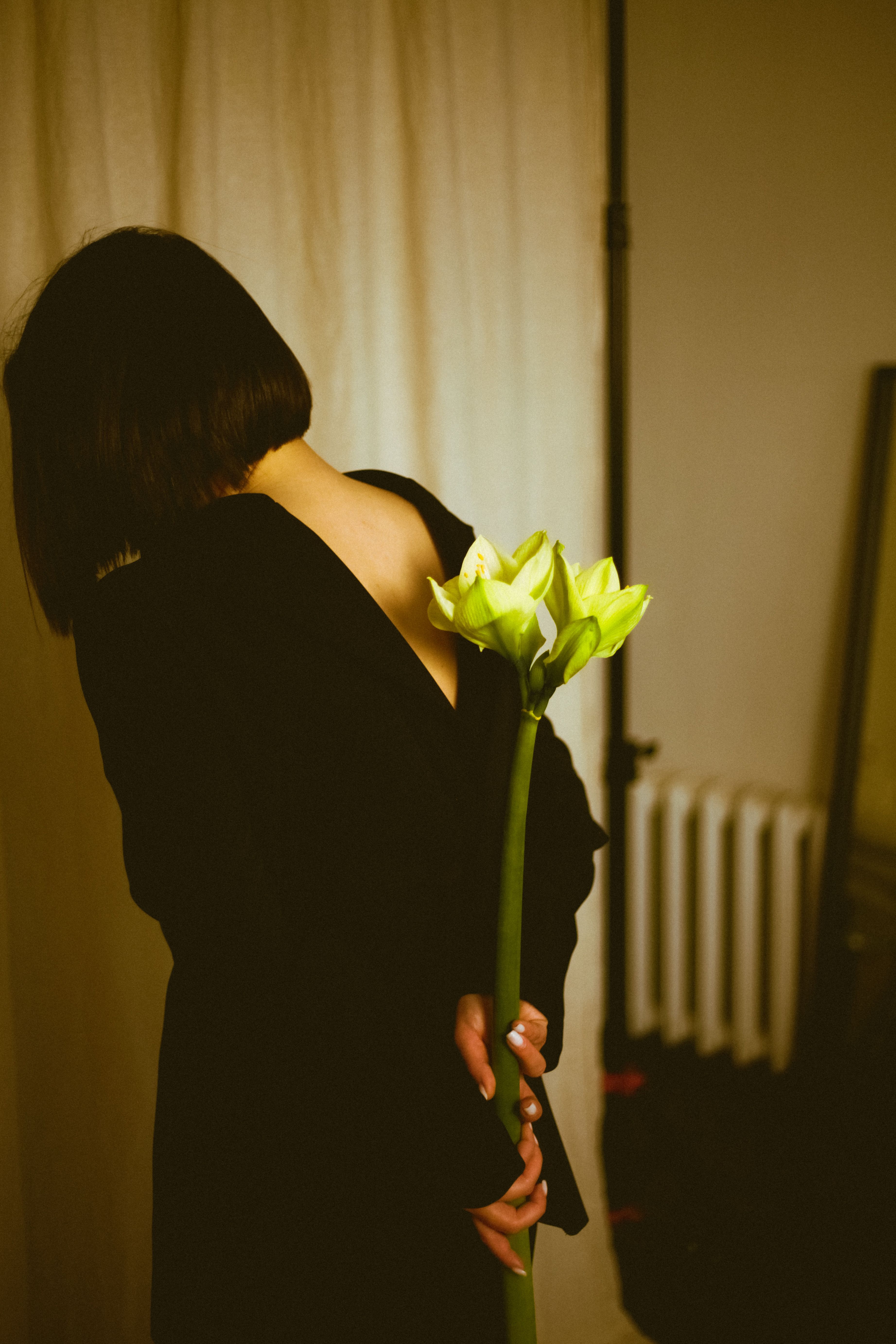 Artistic image of a woman with a lily, photographed indoors with warm tones.