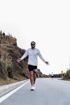 Energetic runner on a mountain road during a marathon against a cloudy sky.