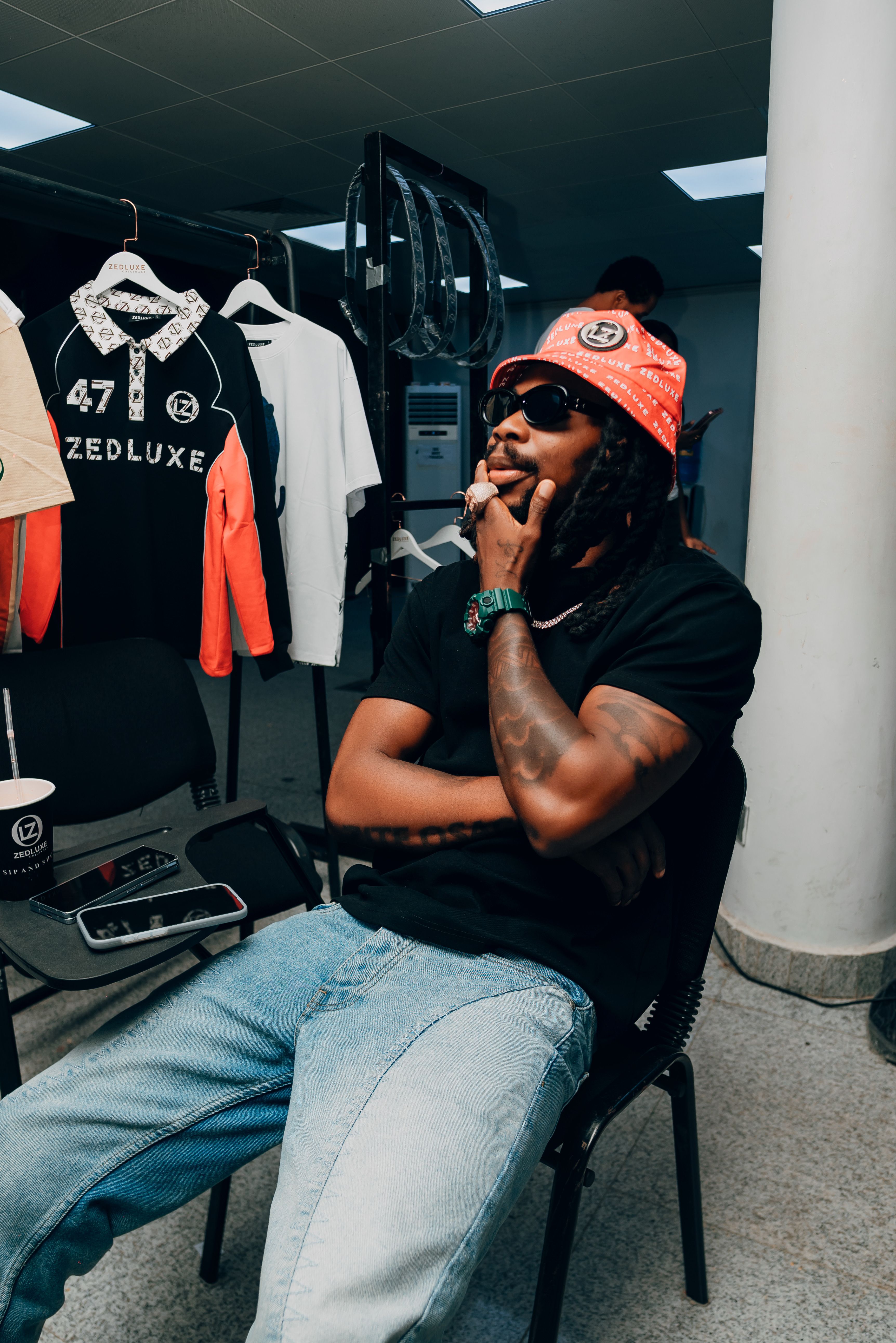 Man sits in a clothing store wearing casual fashion, Lagos, Nigeria.