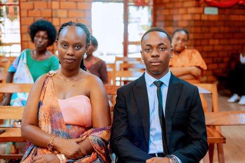 Free A man and woman dressed elegantly, seated in a church with others in the background. Stock Photo
