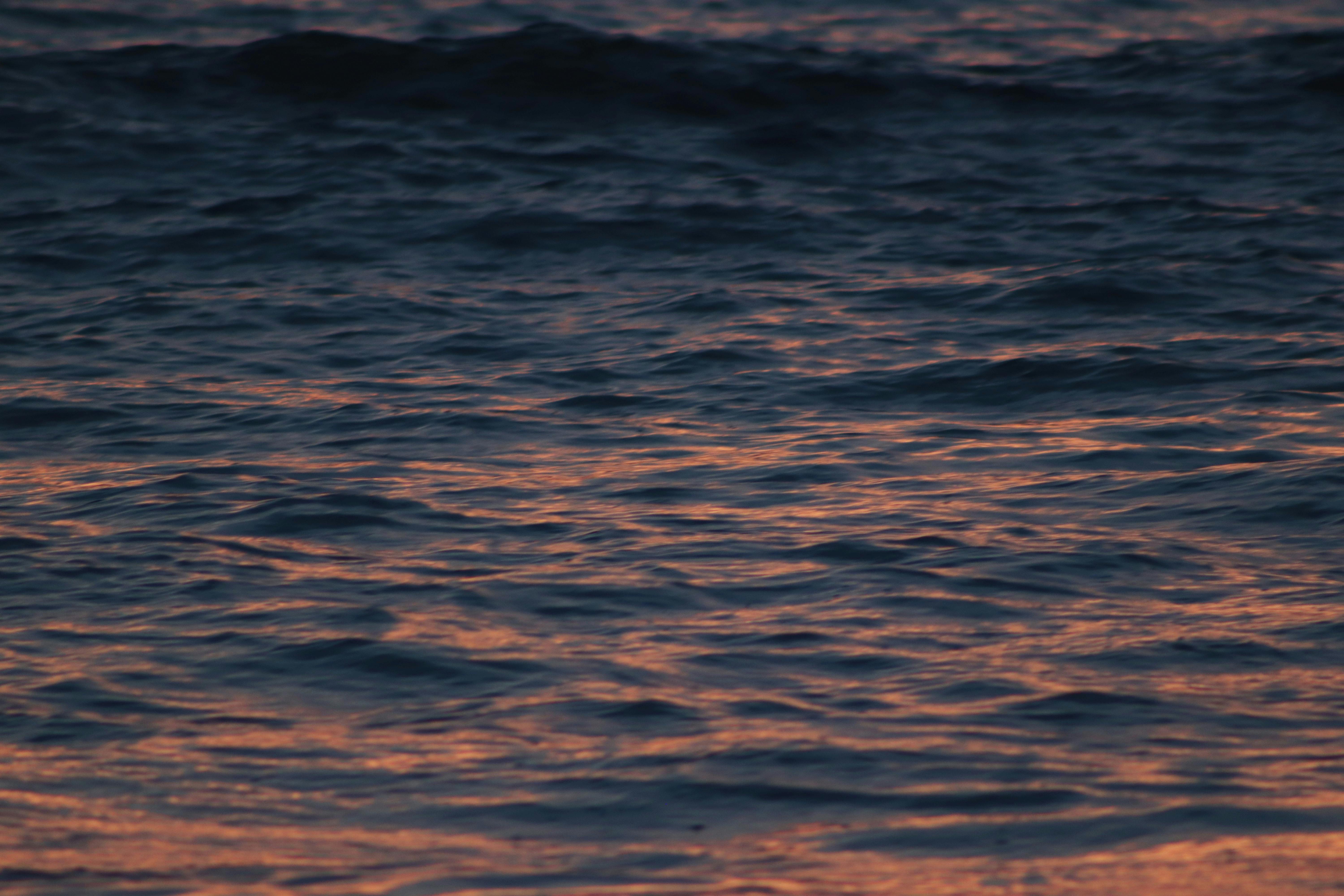 Calm ocean waves reflecting warm sunset colors, creating a serene and captivating seascape.