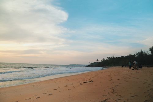 Free Tranquil sunset view on a tropical beach with gentle waves and a distant coastline. Stock Photo