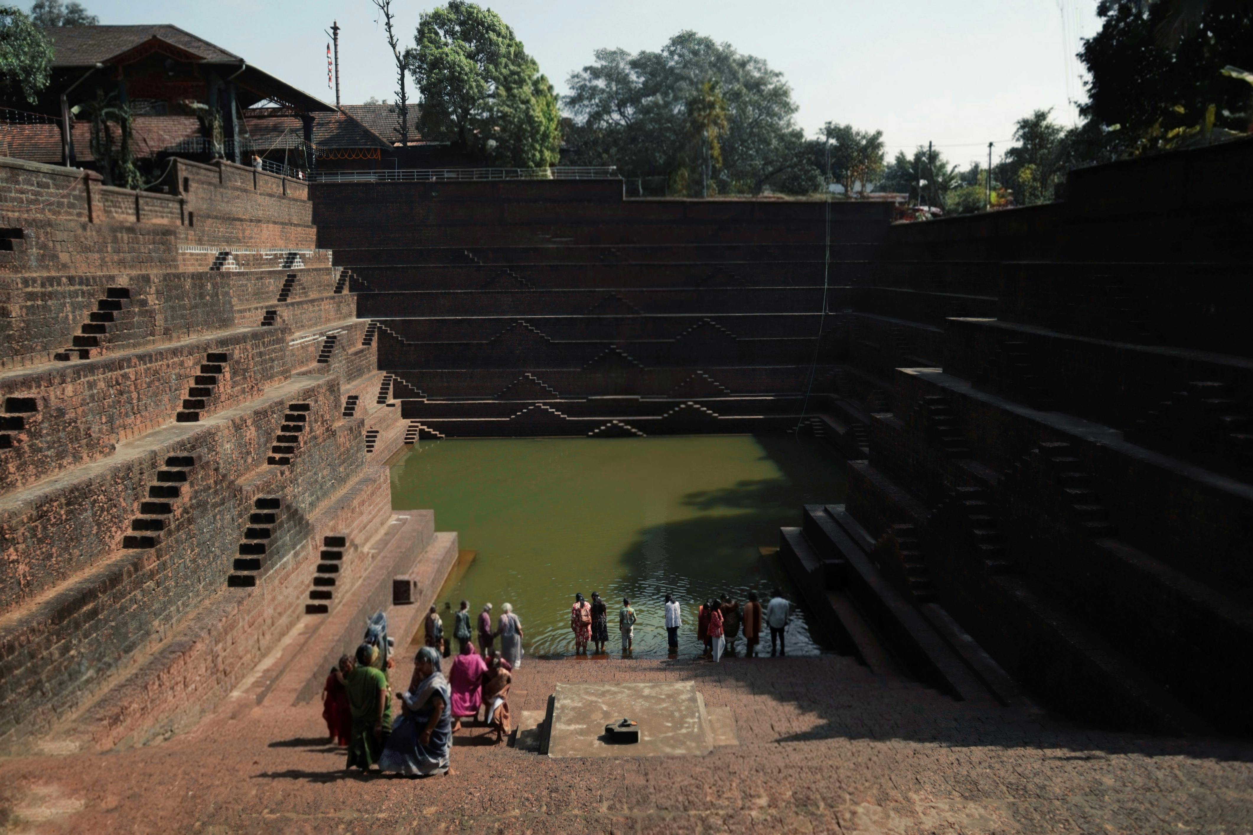 A group of people exploring a historic stepwell in India, showcasing ancient architecture.