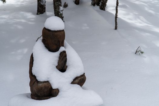 A serene snow-covered Buddha statue in a tranquil winter setting in Santa Fe.