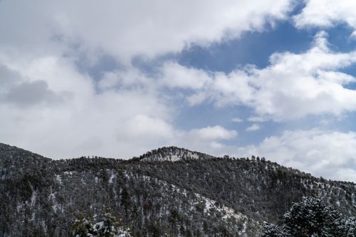 Free A scenic view of the snow-covered Sangre de Cristo Mountains under a partially cloudy sky in Santa Fe, New Mexico. Stock Photo
