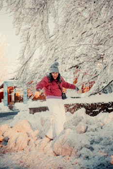 Happy woman in winter attire playing in snowy park on a sunny day.