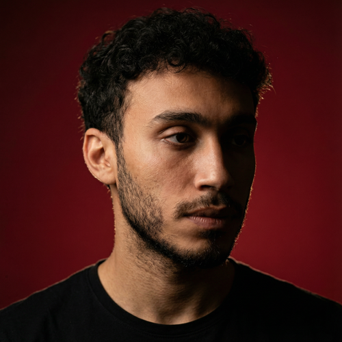 Free A thoughtful portrait of a young man against a deep red backdrop, conveying emotion. Stock Photo