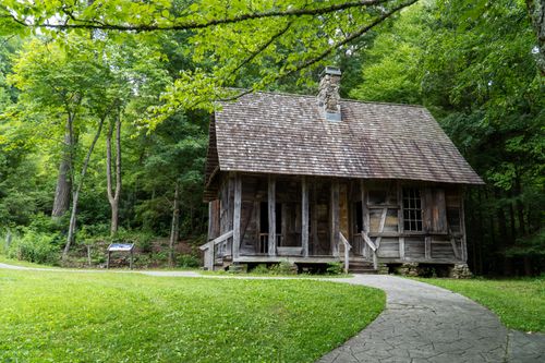 Free A rustic log cabin nestled in lush green woods, capturing Appalachian heritage. Stock Photo