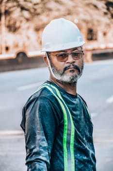 Construction worker in reflective gear standing on a city street.