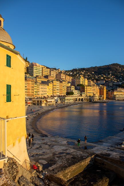 Charming seaside view of colorful buildings along Camogli, Liguria coastline at sunset.