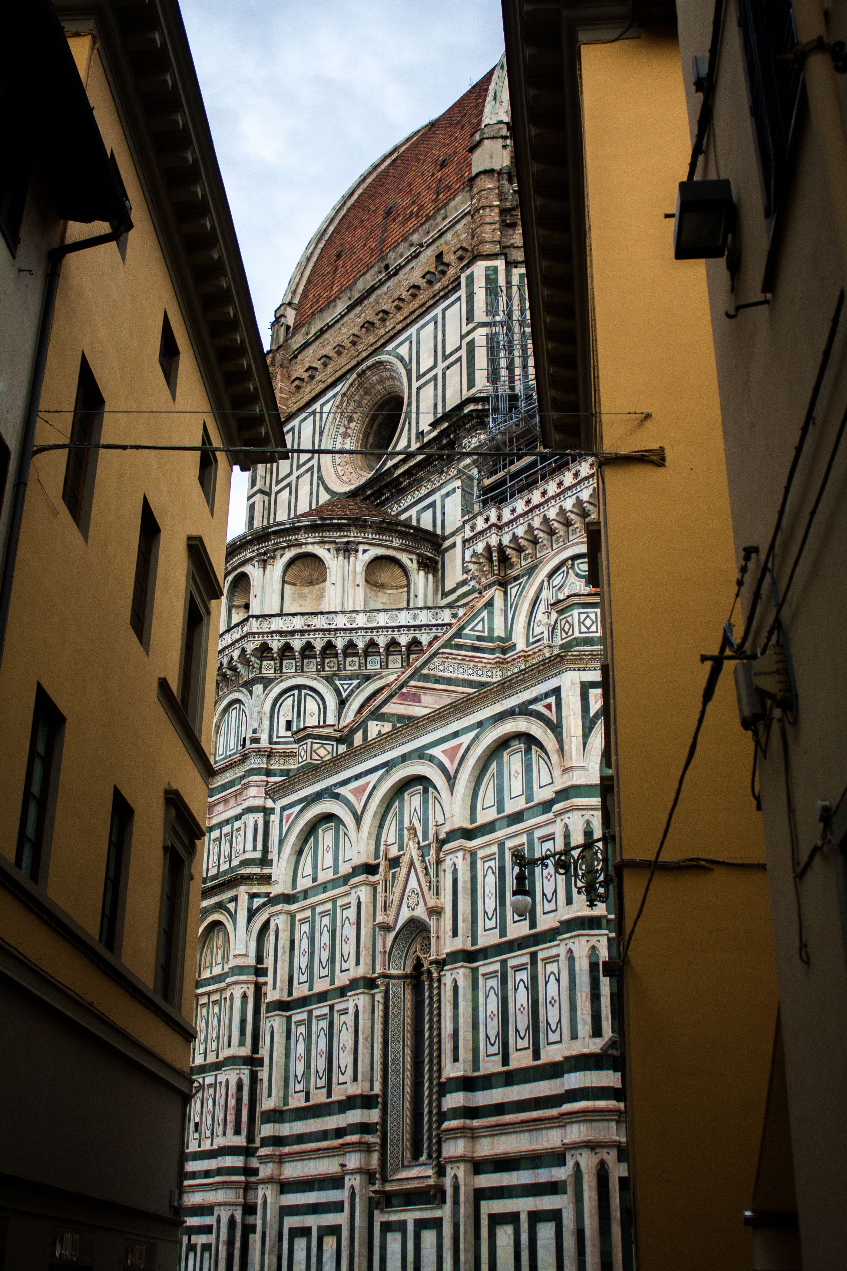 Beautiful view of the Florence Cathedral's dome framed by alley buildings showcasing intricate architecture.