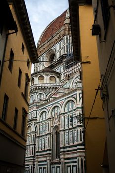 Beautiful view of the Florence Cathedral's dome framed by alley buildings showcasing intricate architecture.