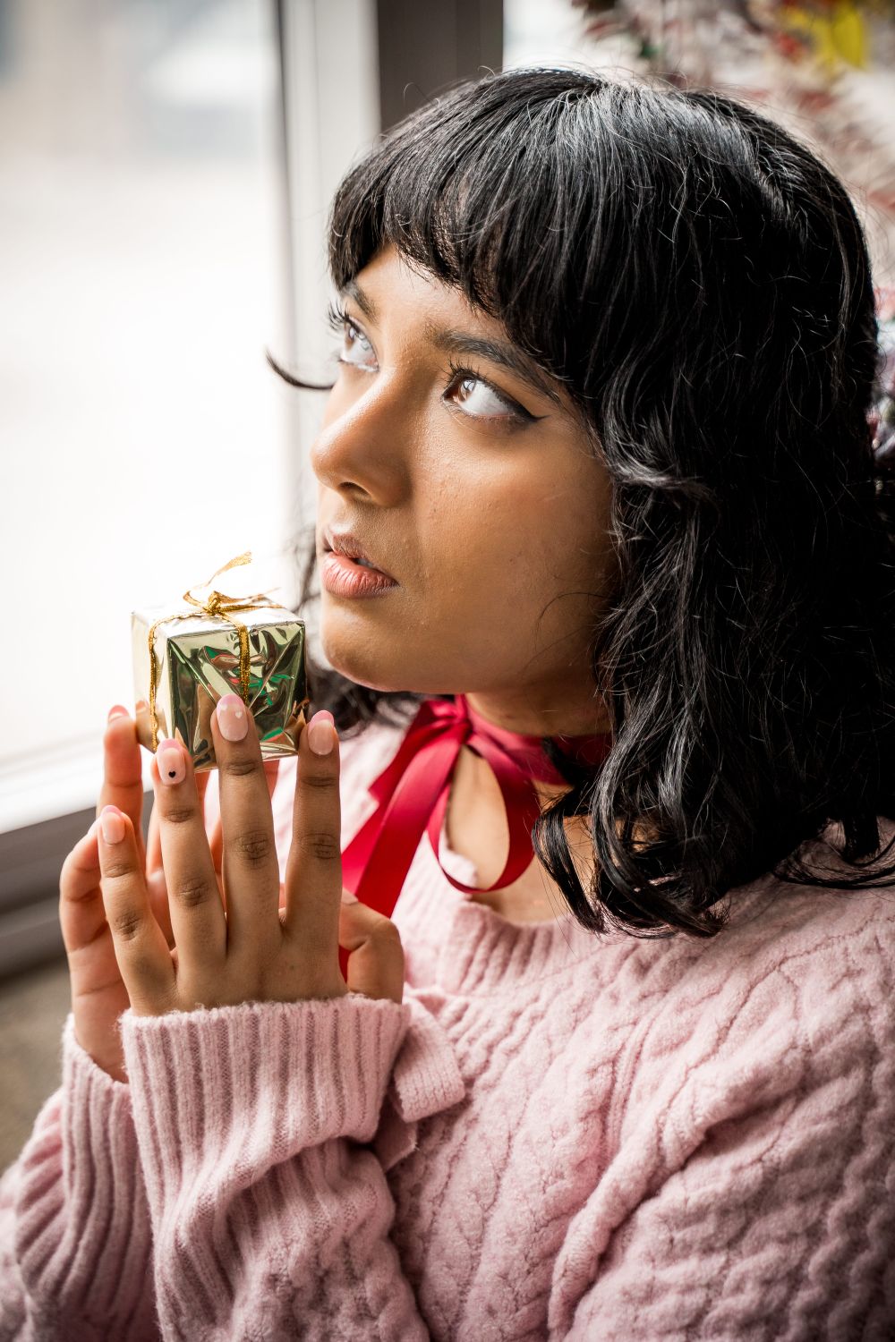 Young Woman Holding Gift Looking Thoughtful · Free Stock Photo