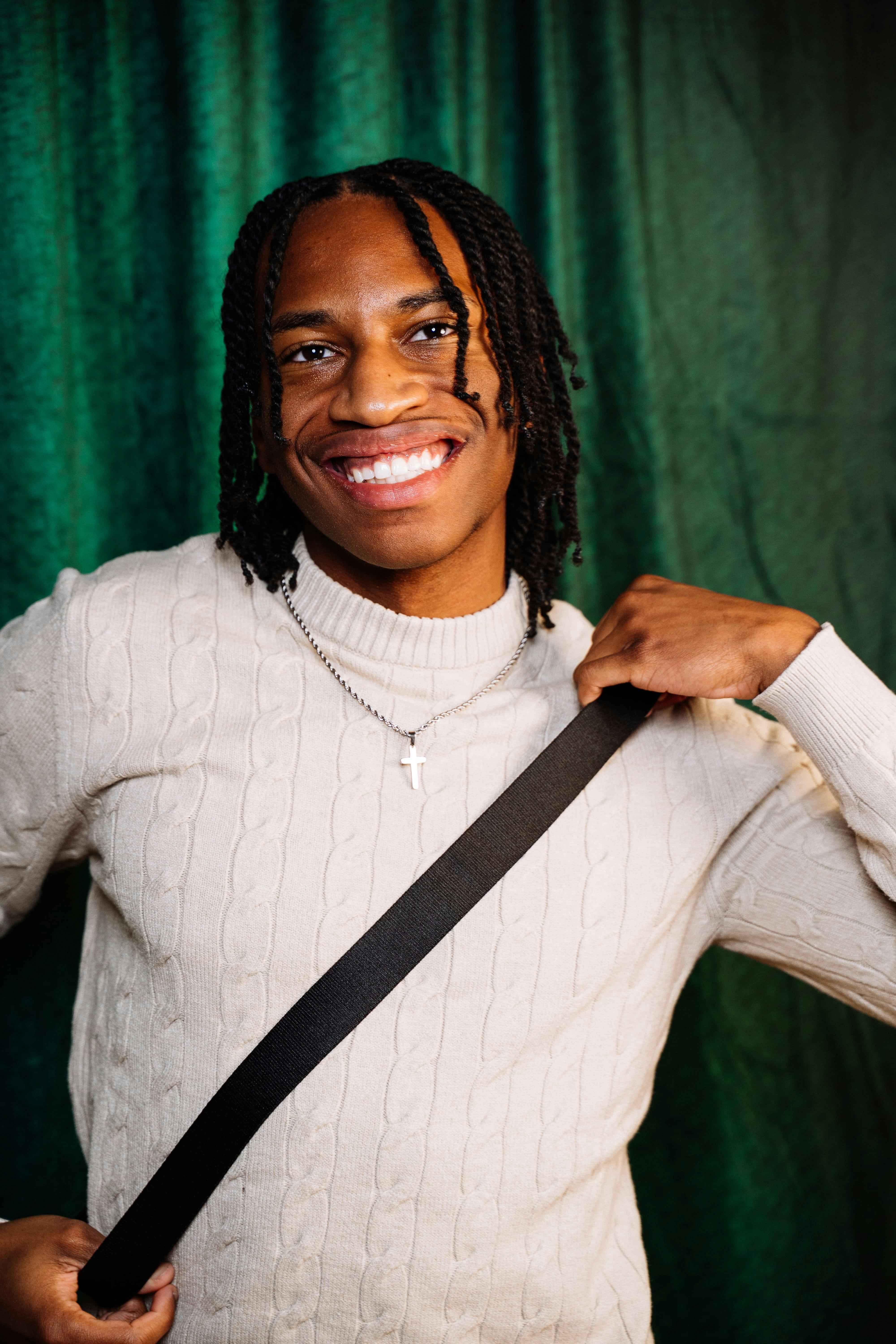 Portrait of a smiling young man in a cozy sweater with a vibrant green background.