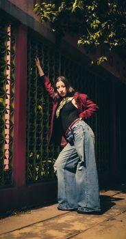 A young woman striking a pose in a fashionable outfit against a vibrant urban backdrop.
