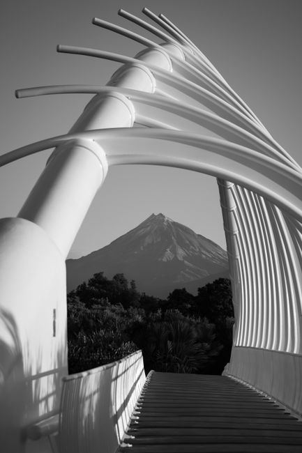 Black and white view of Te Rewa Rewa Bridge with Mount Taranaki in the background.