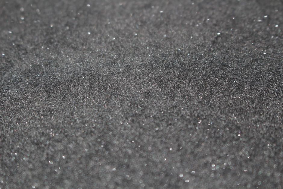 A detailed view of the planet Mercury showing its cratered, textured gray surface with subtle variations of charcoal, silver, and slate gray.