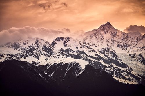Free Breathtaking view of snow-covered mountains under an orange sunset sky, capturing nature's beauty and tranquility. Stock Photo