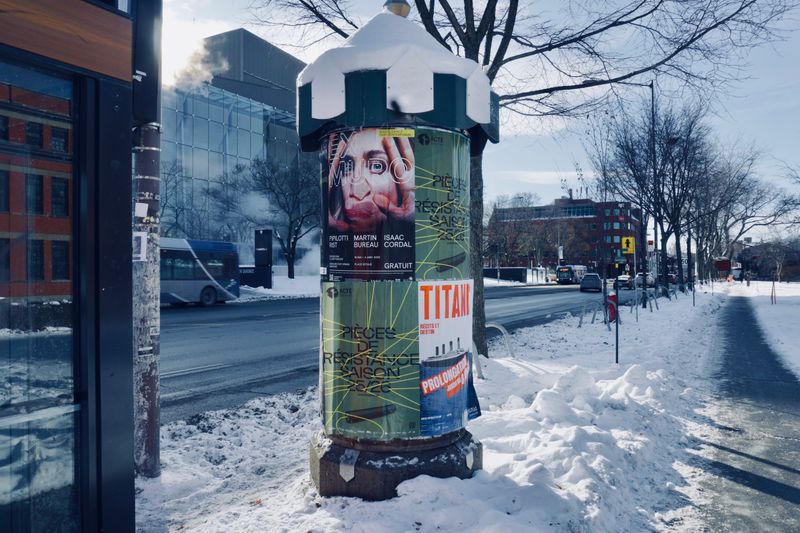 Snow-covered street with a cylindrical advertisement pillar on a winter day.