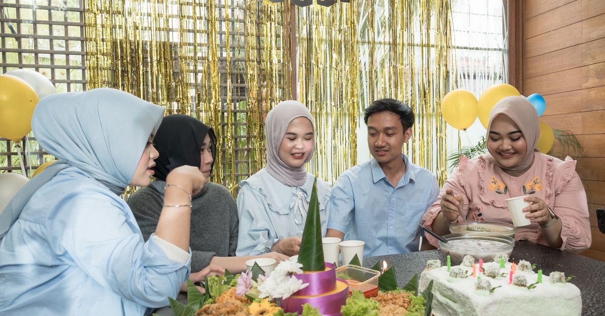 A family smiling together at a community event with food and decorations in the background